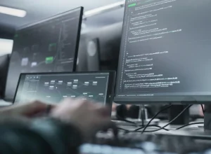 Software developers coding at desks with multiple monitors displaying code and dashboards.