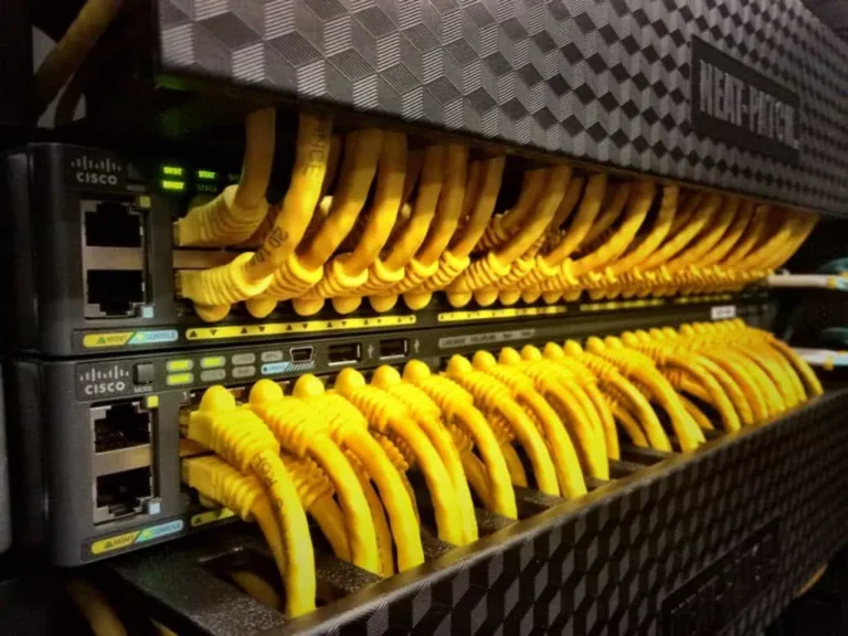 Row of Cisco network switches with numerous yellow Ethernet cables connected.
