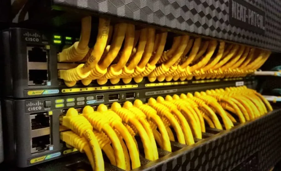 Row of Cisco network switches with numerous yellow Ethernet cables connected.